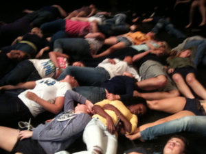 students laying on the ground during college hypnosis show
