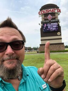 Casino Hypnotist CJ Johnson in front of the marquee with his image on it at Coushatta Casino